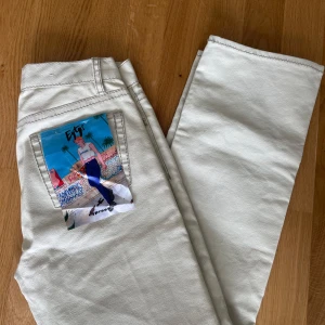Beige jeansbyxor från Eytys med tryckt bakficka - Säljer ett par beige jeansbyxor från Eytys med rak passform och unikt tryck på ena bakfickan. Byxorna har klassisk femficksdesign, dragkedjegylf och vita sömmar. Perfekta för dig som vill sticka ut med en cool detalj på jeansen.