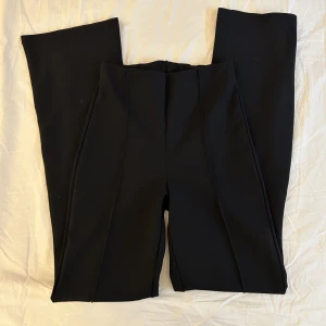 Svarta bootcut-kostymbyxor från Gina Tricot - Säljer ett par svarta bootcut-byxor från Gina Tricot i stretchigt material. Byxorna har långa ben med utsvängda benslut. 