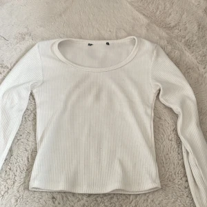 Vit ribbad croppad långärmad topp från newyorker  - Säljer en ribbad vit långärmad topp från newyorker i mjuk bomullsblandning. Tröjan har rund halsringning och slits i nedre ärmarna som jag själv klippt. Säljer då de inte kommer till användning.