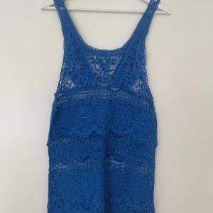 Blå virkad linnetopp - Säljer en blå virkad linnetopp med vackert spetsmönster. Toppen är ärmlös och har en luftig, bohemisk känsla – perfekt för varma dagar eller som strandplagg.