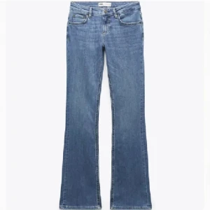 Blå bootcut jeans från ZARA - Säljer ett par klassiska blå bootcut jeans från ZARA. Jeansen har normal passform upptill och utsvängda ben, med fem fickor och dragkedja. Perfekta till sneakers eller boots och tillverkade i mjukt denimtyg. Har en pytte liten reva 