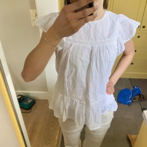 Vit blus med volangärmar - Säljer en söt och luftig vit blus med volangärmar och fina spetsdetaljer. Blusen har en lös passform och är tillverkad i ett lätt och skönt bomullsmaterial, perfekt för varma dagar. Passar lika bra till jeans som till kjol. Det är storlek 158/164 men passar mig jättebra och jag har xs/s🌸💗