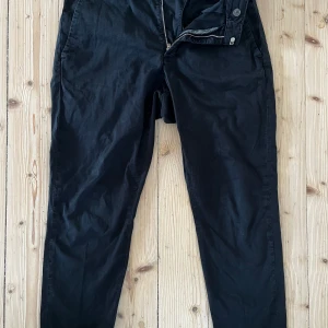 Svarta HOPE byxor st.36 - Säljer ett par svarta chino byxor från HOPE i storlek 36. Byxorna har klassisk passform med dragkedja och knapp framtill samt fickor bak. Perfekta till en stilren look och tillverkade i ett mjukt bomullsmaterial.