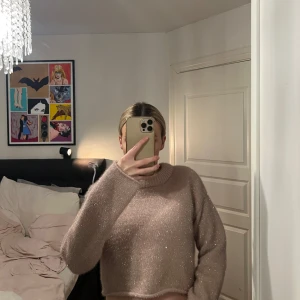 Glittrig croppad tröja i ljusrosa - Säljer en superfin ljusrosa croppad tröja med glittriga inslag. Tröjan har långa ärmar och en rund halsringning. Perfekt för dig som vill ha något mysigt men ändå lite extra.