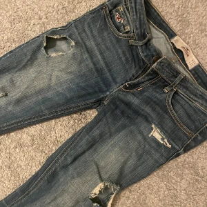 Hollister jeans 24/31 - Säljer ett par blå jeans från hollister med hål. De är lagom i längd på mig som är 165 cm. 