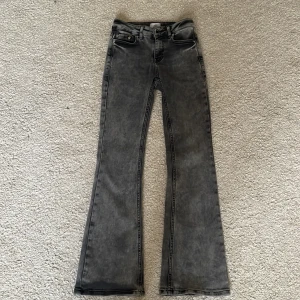 Grå bootcut jeans från Grunt - Snygga grå jeans från Grunt med bootcut-passform. Jeansen har klassisk femficksdesign, bälteshällor och dragkedja med knapp framtill. Perfekta för dig som gillar en retroinspirerad look.