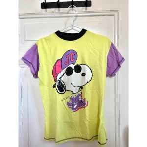 Ljusgrön och lila Snoopy t-shirt - Skitcool Snoopy t-shirt i ljusgrönt med lila ärmar och svart krage. ✨ mini fläck på baksidan tröjan som borde gå bort med rätt verktyg