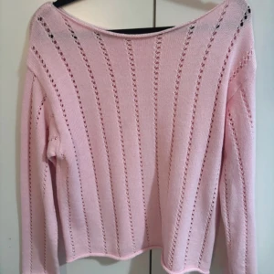 Ljusrosa stickad tröja med hålmönster - Säljer en ljusrosa stickad tröja med lång ärm och dekorativa hål i ränder längs hela tröjan. Tröjan har en rak passform och är mjuk och lätt, perfekt för lager-på-lager.