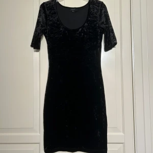 Svart sammetsklänning från Lindex - Säljer en svart sammetsklänning från Lindex i storlek XS. Klänningen har korta ärmar, rundad urringning och en figurnära passform. Perfekt för dig som gillar klassisk och stilren look.