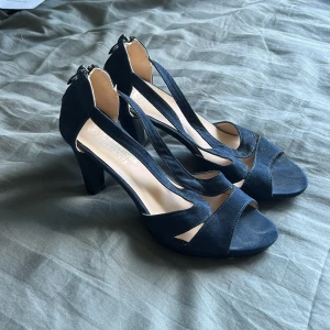 Mörkblå klackade sandaler med öppen tå - Säljer ett par mörkblå sandaler med klack och öppen tå. Skorna har snygga korsade remmar och dragkedja bak för enkel påtagning. Perfekta om du inte vill klä upp dig för mycket. Jag säljer pgr av att dem är ett snep för stora