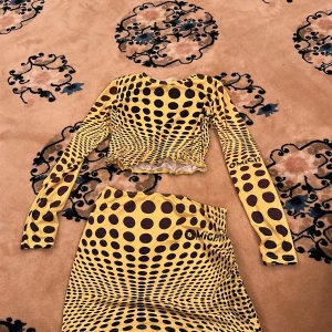 Gul och brun prickig kjol från MICH - Säljer en kort kjol i gul och brun med prickigt mönster. Kjolen har snörning i sidan och är i ett stretchigt material. Perfekt för dig som vill sticka ut med ett unikt mönster.