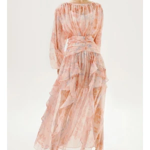 Ljusrosa blommig långklänning med volang - Romantisk långklänning i ljusrosa med blommigt mönster och volangdetaljer. Helt ny, oanvänd. Etiketten står fortfarande på. Perfekt till sommaren och superelegant.