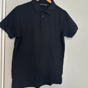 Svart pikétröja med krage - Klassisk svart pikétröja med krage och knappslå framtill. Perfekt till både vardag och mer uppklädda tillfällen. Kortärmad och i mjukt material som andas. Lager157 den va för stor köpte 150 säljer för 100 