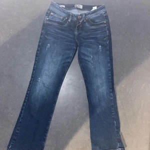 Blå jeansbyxor från LTB Valerie - Säljer ett par klassiska blå jeansbyxor från LTB, modell Valerie. Byxorna har raka ben, fem fickor och snygga kontrastsömmar. De har normal passform och stängs med dragkedja och knapp. Perfekta till vardags för en avslappnad stil. Lowrise bootcut 