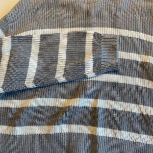 Gråvit randig stickad tröja från H&M - Säljer en stickad tröja från H&M i grått och vitt med breda horisontella ränder. Tröjan har lång ärm och är perfekt för kyligare dagar. Enkel och stilren design som passar till det mesta.
