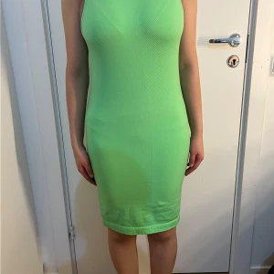 Grön ärmlös tight klänning - Säljer en fräsch grön ärmlös klänning i tight passform. Klänningen är kort och har en enkel, stilren design utan mönster eller detaljer. Perfekt för dig som gillar färg och vill sticka ut.