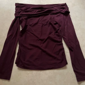 Vinröd offshoulder topp från Gina Tricot - Säljer en vinröd långärmad offshoulder topp från Gina Tricot. Toppen har en snygg draperad kant upptill och är figurnära i modellen. Perfekt för dig som gillar trendiga och stilrena plagg. Har använt två gånger och säljer den för att den inte kommer till användning!!