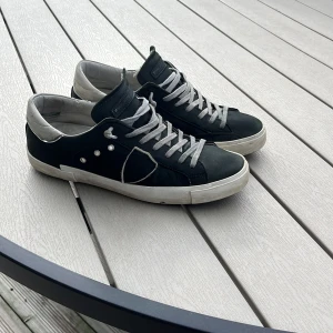 Svarta sneakers från Philippe Model - Snygga mörk gröna sneakers från Philippe Model med vita detaljer och snörning. Skorna har en klassisk design med rund tå och en bekväm passform. Perfekta för en stilren look.