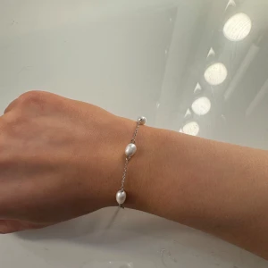 pärlarmband edblad  - Elegant silverarmband med vita pärlor jämnt fördelade längs kedjan. Perfekt för att ge en stilren touch till din outfit. Armbandet har en justerbar kedja för perfekt passform. nyskick 