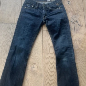 Mörkblå jeans från Replay - Snygga mörkblå jeans från Replay med broderad detalj på bakfickan. De har en klassisk femficksdesign och är tillverkade i Italien. Perfekta för en stilren look.