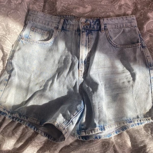Ljusblå jeansshorts Gina tricot  - Säljer ett par ljusblå jeansshorts med klassisk femficksdesign. De har en knapp och dragkedja framtill och är perfekta för sommardagar. Passar till en avslappnad stil och är ett måste i garderoben. 🩳✨