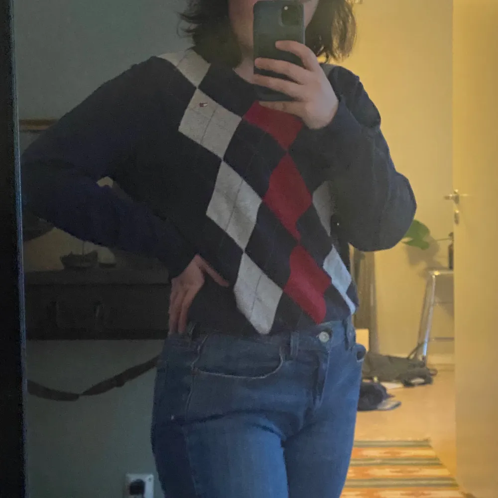 Snygg tröja från Tommy Hilfiger med ett klassiskt argylemönster i blått, rött och vitt. Tröjan har en v-ringad hals och långa ärmar, perfekt för en stilren look. Passar bra till både jeans och chinos.. Neuletakit & Villapaidat.