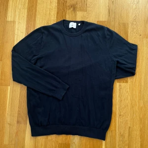 Mörkblå crewneck från Bläck - Säljer en stilren mörkblå tröja från Bläck. Tröjan har en klassisk design med rund hals och långa ärmar. Perfekt för en avslappnad och snygg look. Passar bra till både jeans och chinos.