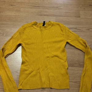 Gul ribbad tröja från H&M - Säljer en snygg gul ribbad tröja från H&M i storlek XS. Tröjan har långa ärmar och en bekväm passform som passar perfekt för höst och vår. Perfekt för att liva upp garderoben med lite färg! 🌟