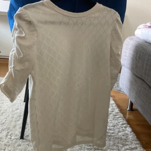 Vit tröja från My Wear Woman - Säljer en stilren vit tröja från My Wear Woman med ett diskret rutmönster. Tröjan har trekvartsärmar och en rund halsringning. Perfekt för en avslappnad look. Passar till ett par kostymbyxor eller jeans men även en kjol. Använt 2-3 gånger bara