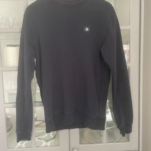 Svart tröja från Scotch & Soda - Säljer en stilren svart tröja från Scotch & Soda. Tröjan har långa ärmar och en rund halsringning. Perfekt för en avslappnad look.