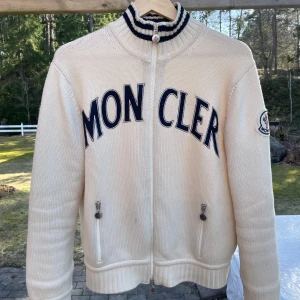 Moncler cardigan vit stickad - Moncler cardigan vit stickad.   Om du söker en unik och snygg stickad moncler cardigan till våren och sommaren så är det här något för dig!!!  Skick 9-10. Stl M. Retail 12-15.000kr mitt pris 7499. Byten kan vara intressant, i skor stl 43 och kläder M-L. 