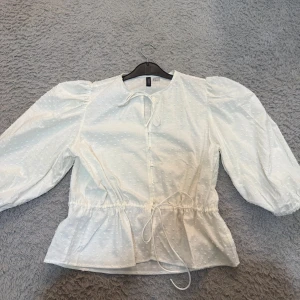 Blus med knytning  - Säljer nu denna extremt fina blusen som är helt oanvänd. Den har knytning vid både halsen och magen och har knappar emellan. Är inte genomskinlig och passar perfekt inför våren!