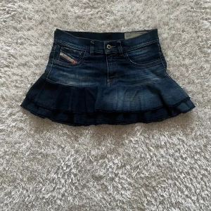 Jeanskjol med volang från Diesel - En lågmidjad jeanskjol omsydd från ett par jeans Midjemått tvärsöver - 35 cm Längd - 30 cm