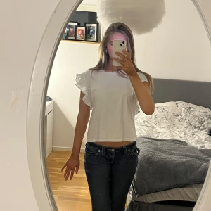 Vit blus från Zara - Säljer en söt vit blus från Zara med volangdetaljer på ärmarna. Perfekt för en stilren och chic look. Blusen har en normal passform och är tillverkad i ett mjukt material.💖