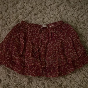 Blommig kjol från Brownie - Säljer en söt blommig kjol. Kjolen har volanger och en bekväm resår i midjan. Perfekt för en somrig look!