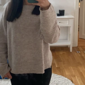 Beige stickad tröja - Mysig beige stickad tröja med långärmad design. Perfekt för kyligare dagar med en avslappnad passform. Enkel och stilren, passar till många olika outfits.