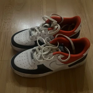 Nike Air Force i vitt, svart och rött - Snygga Nike Air Force sneakers i en fräsch färgkombination av vitt, svart och rött. Skorna har klassisk snörning och en bekväm passform. Perfekta för en stilren look. Storlek 38.5. Använd ett fåtal gånger. Tvättar de vid köp. Original box finns ej. Men skickas förmodligen i en annan sko kartong. Hör av er vid funderingar