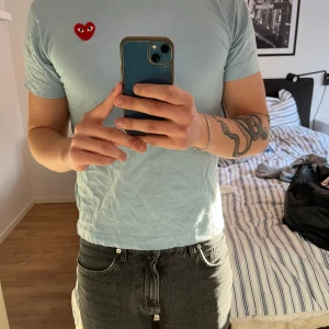Ljusblå t-shirt från Comme des Garçons - Säljer en ljusblå t-shirt från Comme des Garçons med det ikoniska röda hjärtat på bröstet. Nypris är cirka 1200kr