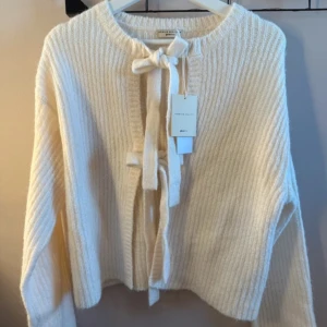 beige kofta från gina tricot  - Säljer en mysig vit ribbad kofta från gina tricot med knytband framtill. Koftan har långa ärmar och super skön. Aldrig använd därför prislapp kvar. Storlek M men passar som S. 