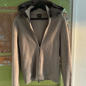 Beige stickad hoodie med dragkedja - Säljer en stilren beige stickad hoodie från Massimo dutti. Tröjan har långa ärmar och ribbade detaljer. Perfekt nu inför våren.
