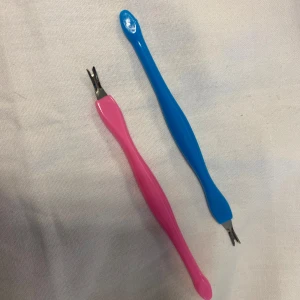 Nagelbandspetare i rosa och blått - Två nagelbandspetare i plast med metallspetsar. Den ena är rosa och den andra är blå. Perfekta för att ta hand om nagelbanden och hålla naglarna snygga.  Helt ny 