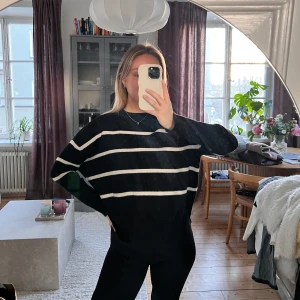 Svart och vit randig tröja - Säljer en svart tröja med vita ränder. Tröjan har en avslappnad passform och långa ärmar, perfekt för en stilren look. Den är enkel att matcha med olika outfits.