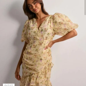 Blommig klänning med volangdetaljer - Säljer en söt blommig klänning i ljusgul ton med volangdetaljer. Klänningen har korta puffärmar och en v-ringad hals. Perfekt för sommarens alla tillfällen! Endast använd en gång så den är i väldigt fint skick!🫶🏼