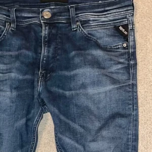 Blå jeans från Replay - Snygga blå jeans från Replay med en klassisk femficksdesign och knappgylf. Jeansen har en lätt tvättad look och är perfekta för en avslappnad stil.