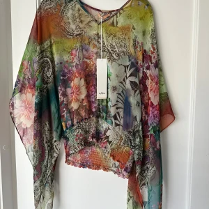 Flerfärgad blommig blus  - Säljer en vacker flerfärgad blus med blommigt mönster. Blusen har en lös passform och är tillverkad i ett lätt och luftigt material. 