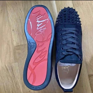 Christian Louboutin skor - Svarta sneakers från Christian Louboutin med nitar på ovansidan och den ikoniska röda sulan.
