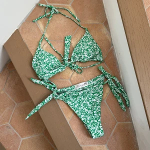 Grön blommig bikini från Design By Si - Snygg grön bikini med vita blommor från Design By Si. Passar inte mig och har aldrig använts. 