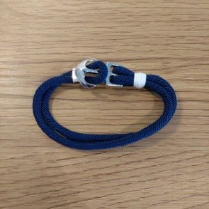 Blått armband med metallspänne - Snyggt blått armband med ett stilrent metallspänne. Armbandet har en enkel design med en vit detalj som ger en fin kontrast. Perfekt för en avslappnad stil.