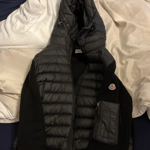Svart monckler kardigang  - Säljer en snygg svart dunjacka från Moncler med quiltad design och dragkedja. Jackan har en hög krage och en liten logotyp på ärmen. Perfekt för kyliga dagar!