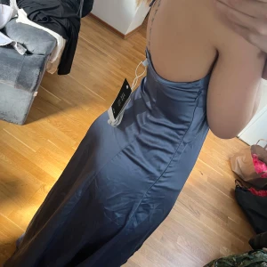 Blå långklänning med öppen rygg - Snygg blå långklänning med öppen rygg och smala axelband. Materialet är satin, och va tänkt som balklänning 